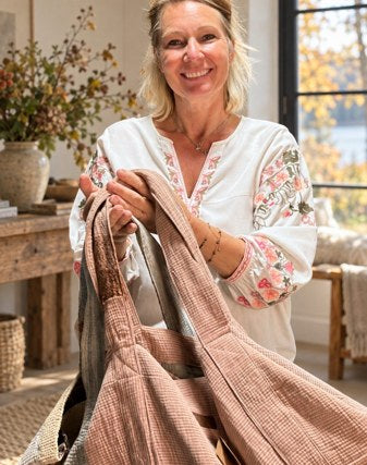 Hanne med et tekstil i hænderne ved vinduet.